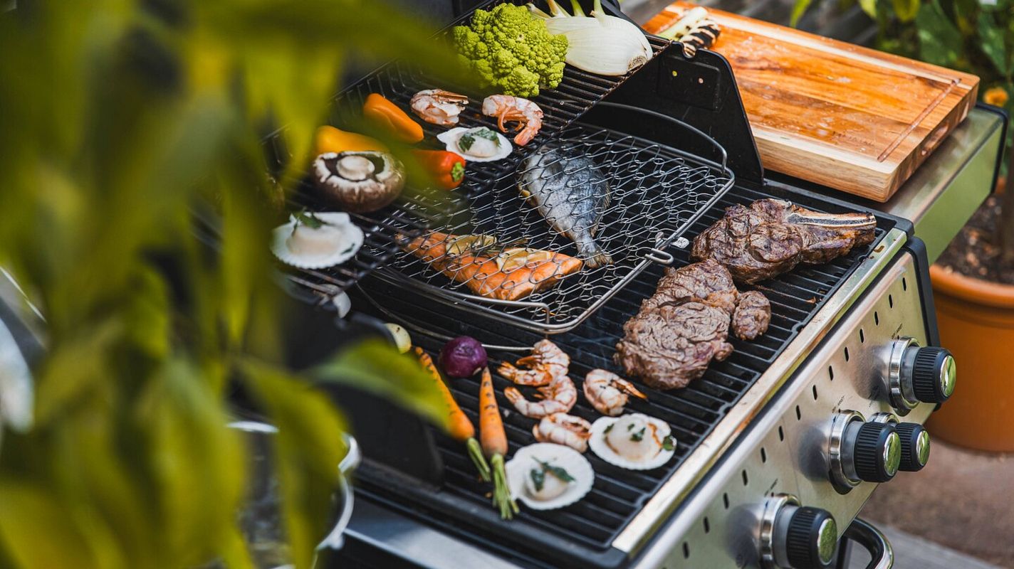 Ein mit unterschiedlichsten, leckeren Speisen belegter Gasgrill. Doch nach dem Essen wartet das Putzen...